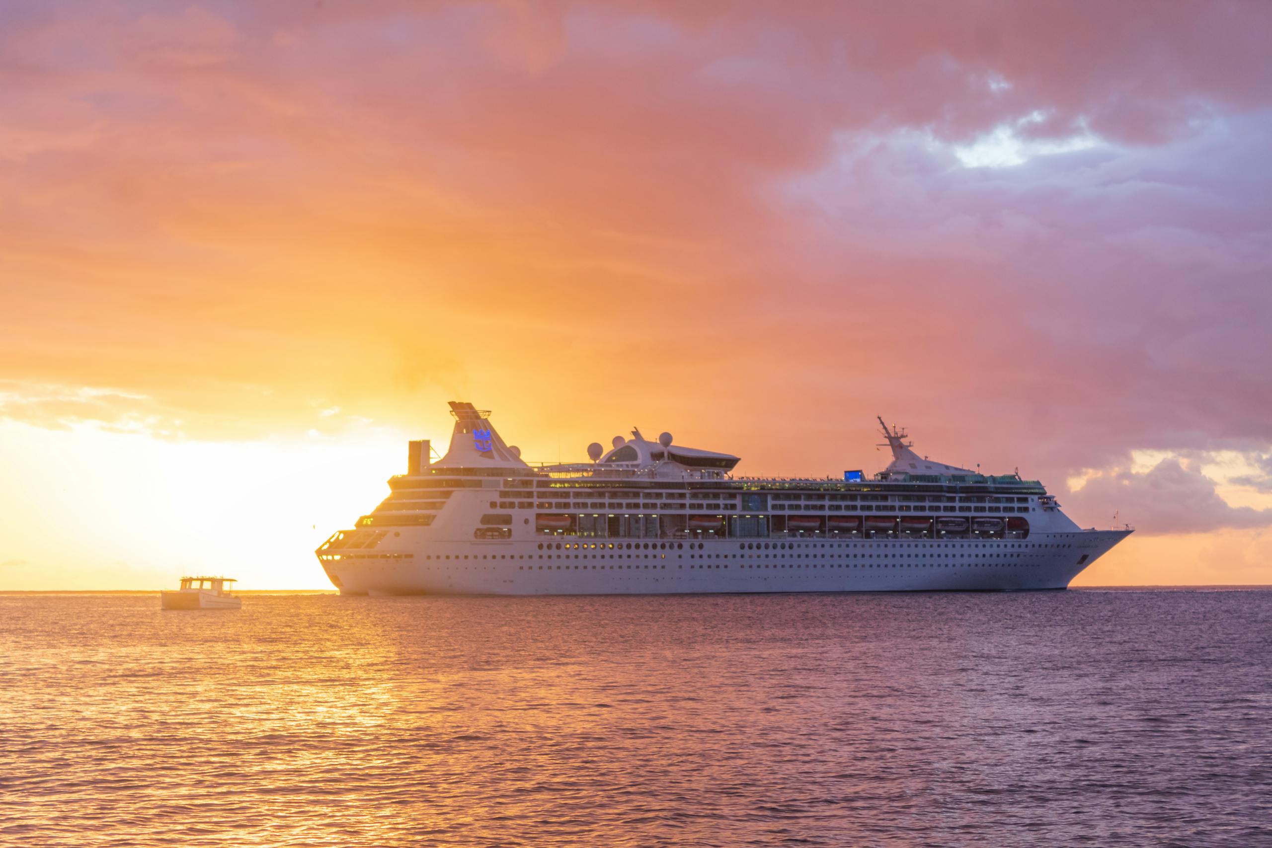 The Essential Cruise Shop - A majestic cruise ship sails at sunset off the coast of Grenada, showcasing luxury travel.
