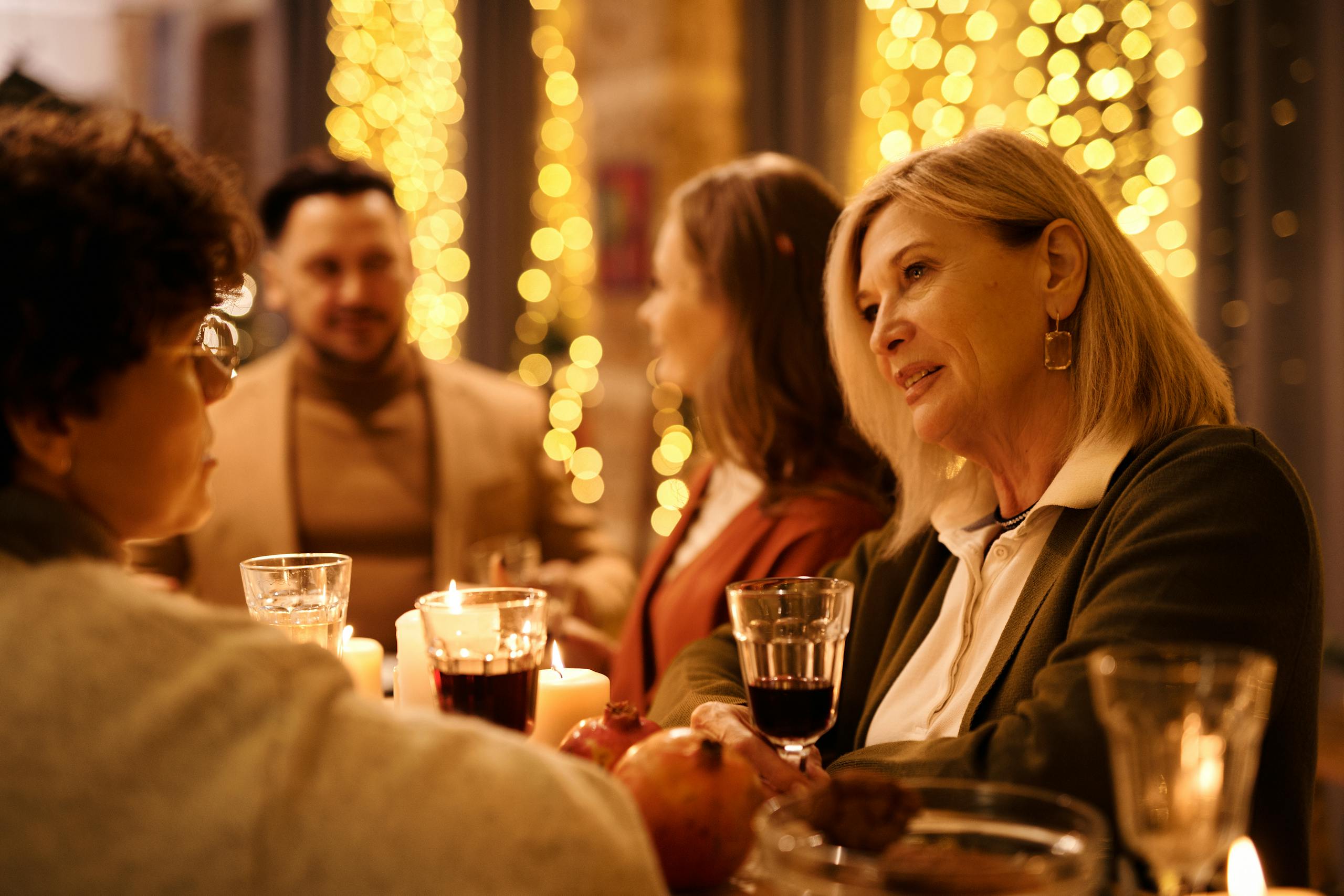 The Essential Cruise Shop Blog - A warm holiday gathering with family and friends enjoying dinner with festive lights.