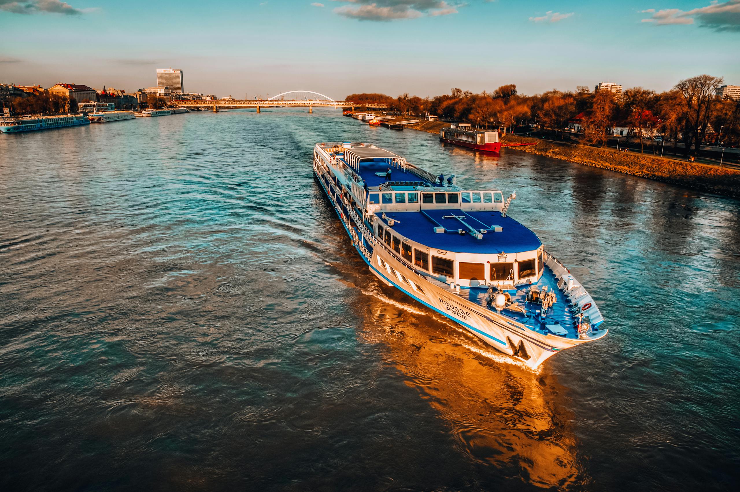 The Essential Cruise Shop Blog - Capture of a cruise ship sailing on the Danube River during sunset in Bratislava, Slovakia.