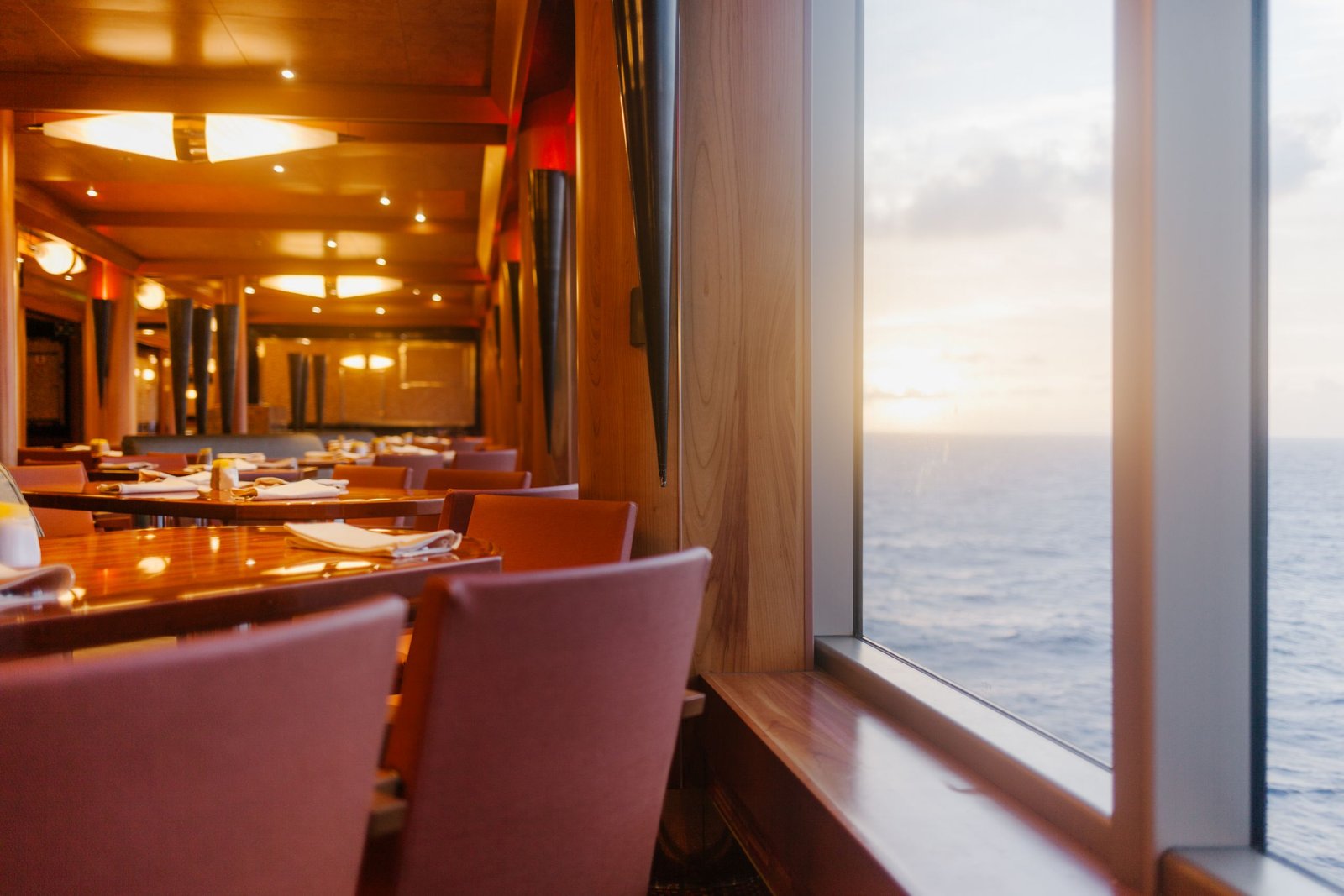 Elegant dining area on a luxury ship overlooking the ocean at sunset, perfect for relaxation - The Essential Cruise Shop Blog
